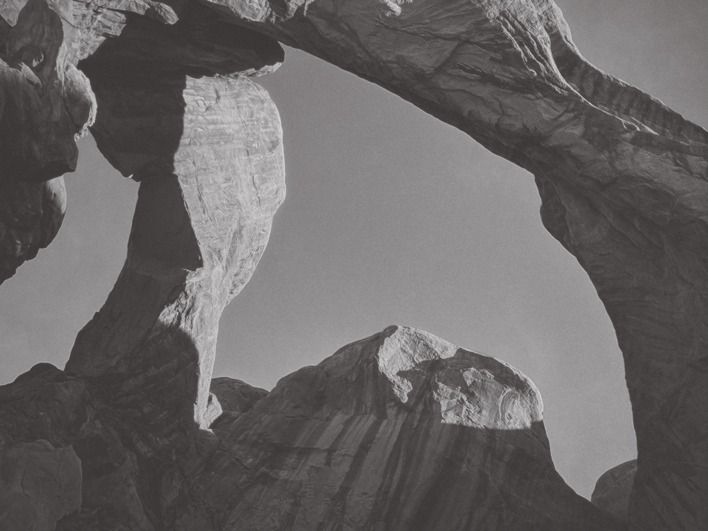 Black and white photograph looking up through a natural stone arch formation