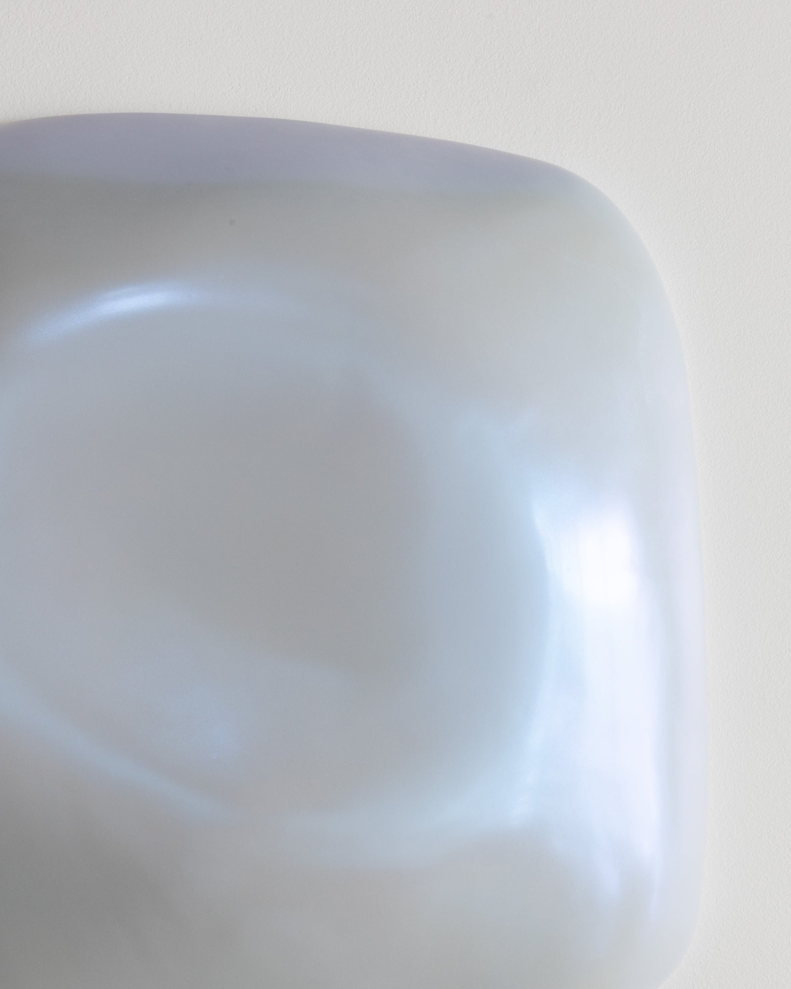 Close-up of a pale blue ceramic fragment with a smooth recessed form