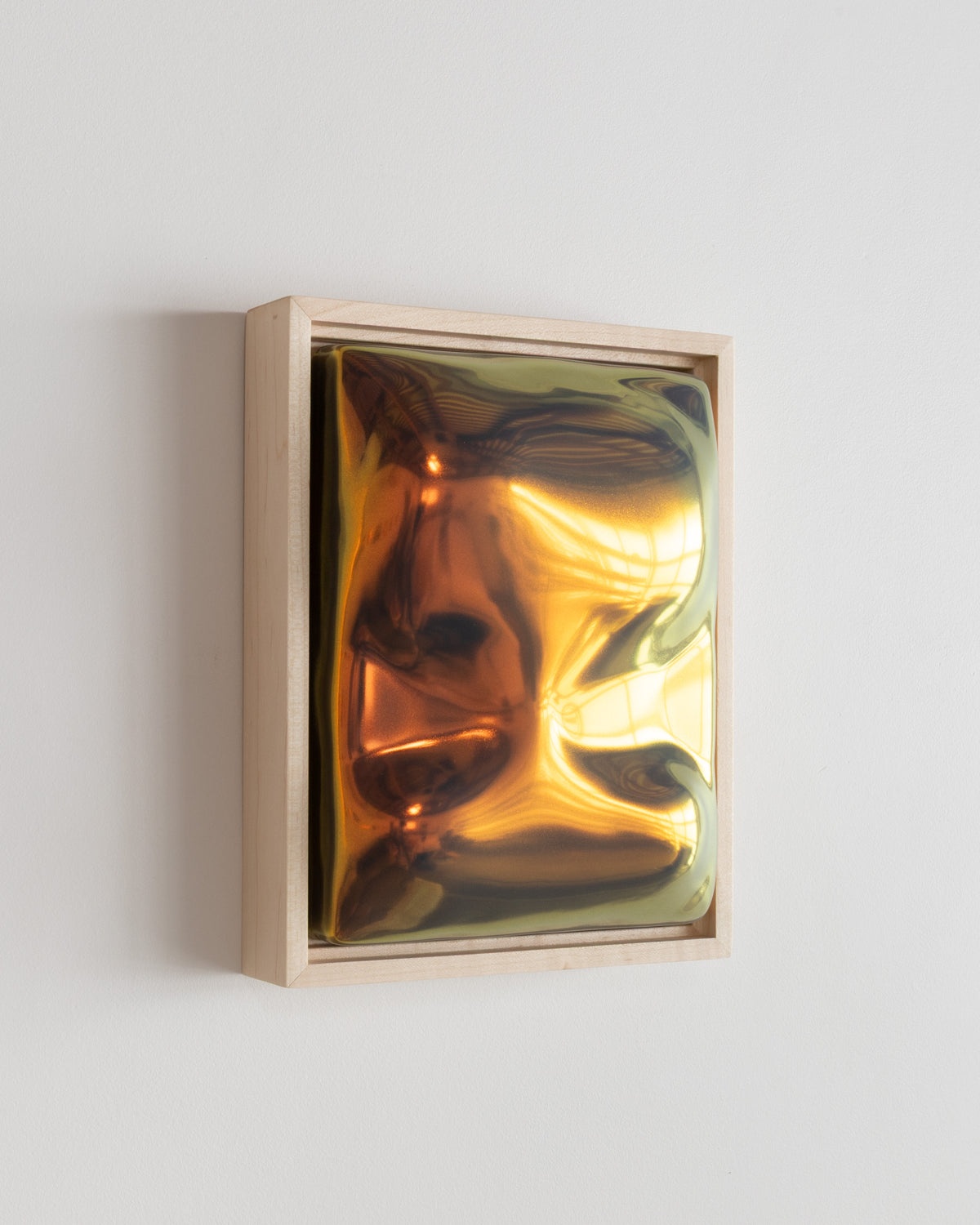 Angled detail of "Artifact" showing the framed ceramic wall relief and iridescent glaze