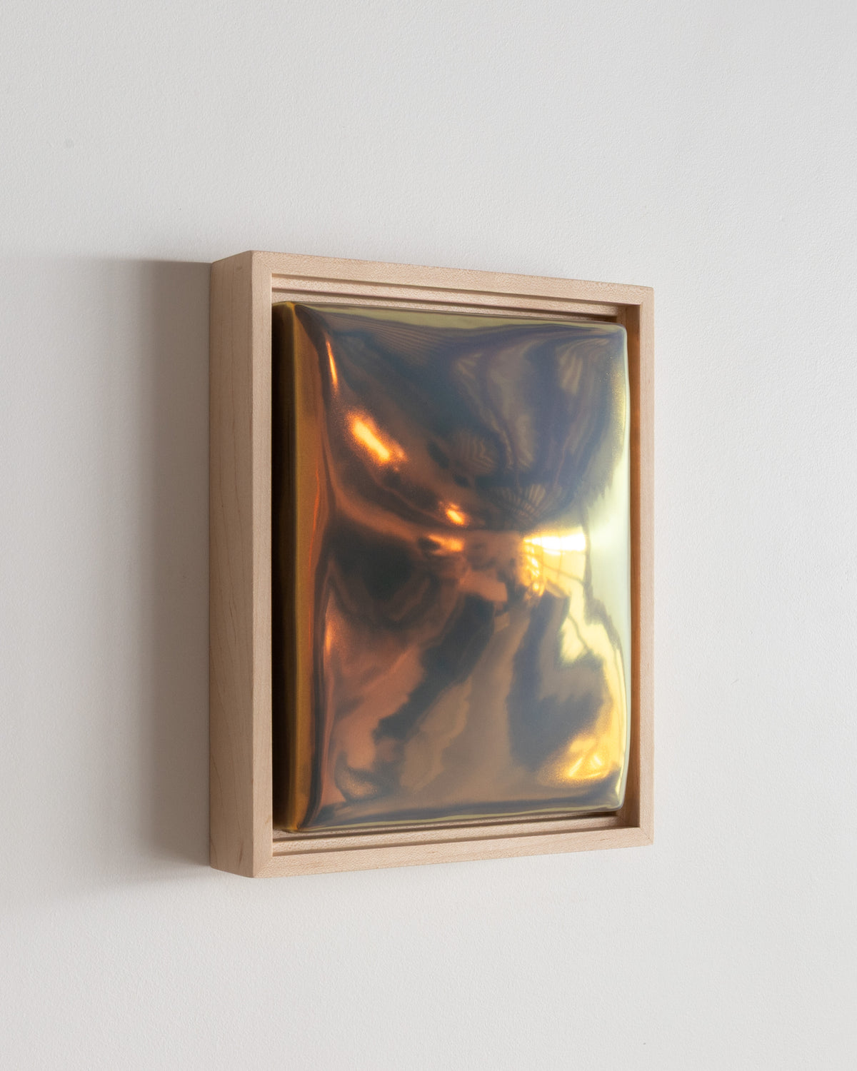 Angled detail of "Convex" showing the framed ceramic wall relief and iridescent glaze