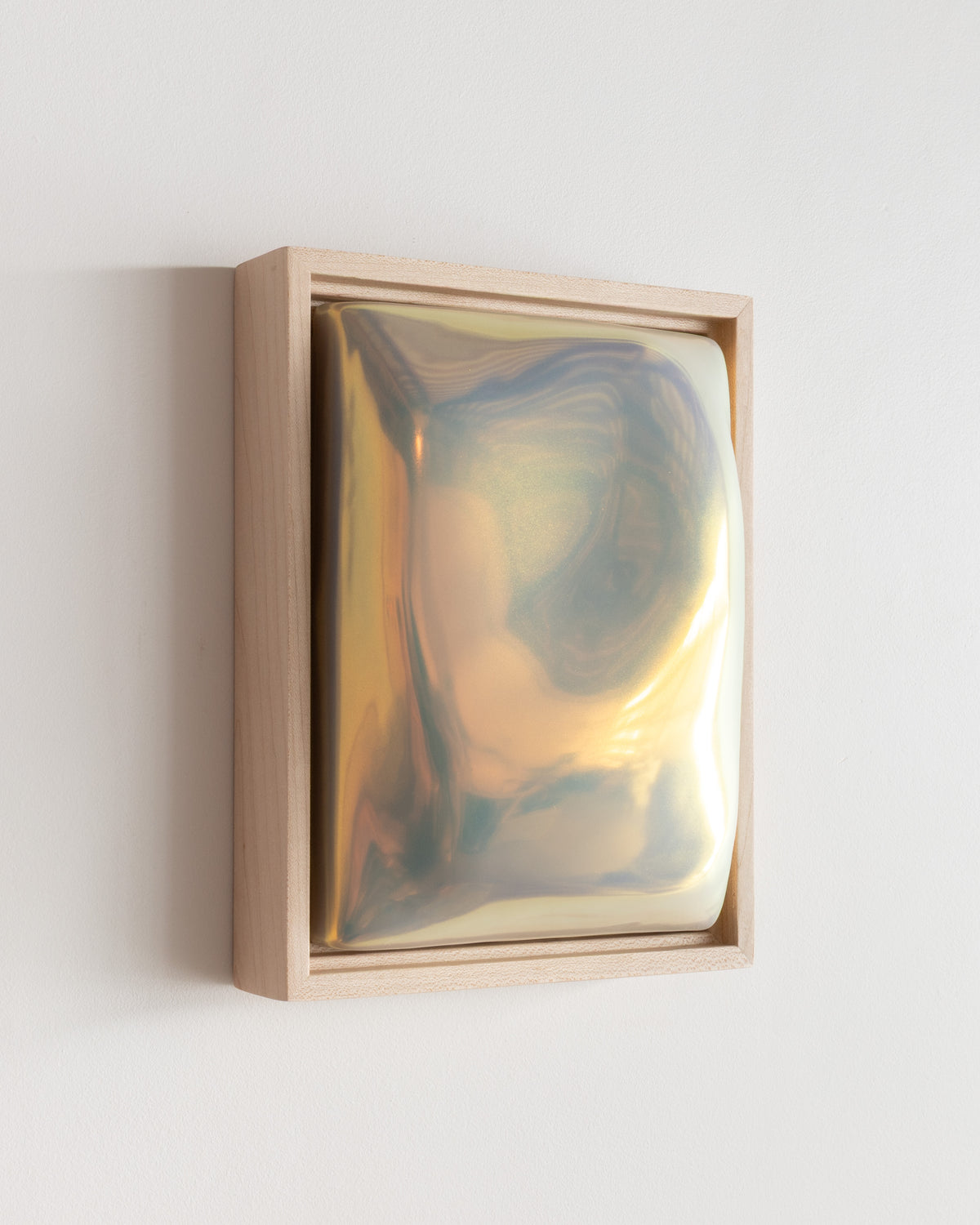 Angled detail of Fold showing the framed ceramic wall relief and iridescent glaze