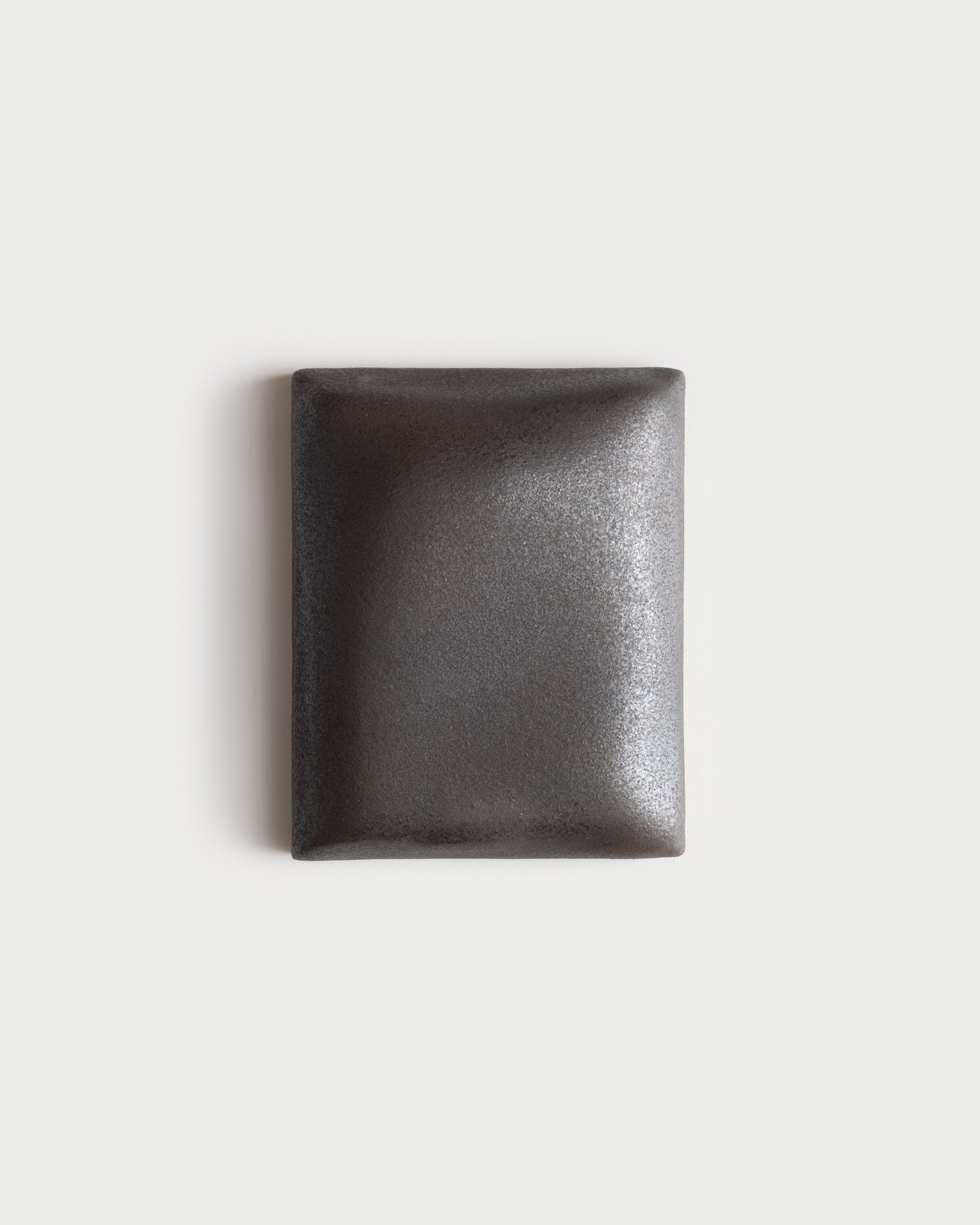 Small dark stone ceramic wall relief on a white wall