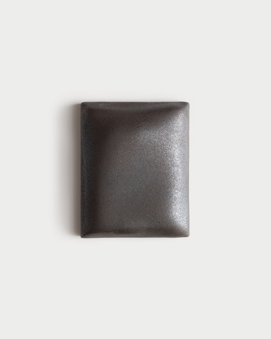 Small dark stone ceramic wall relief on a white wall