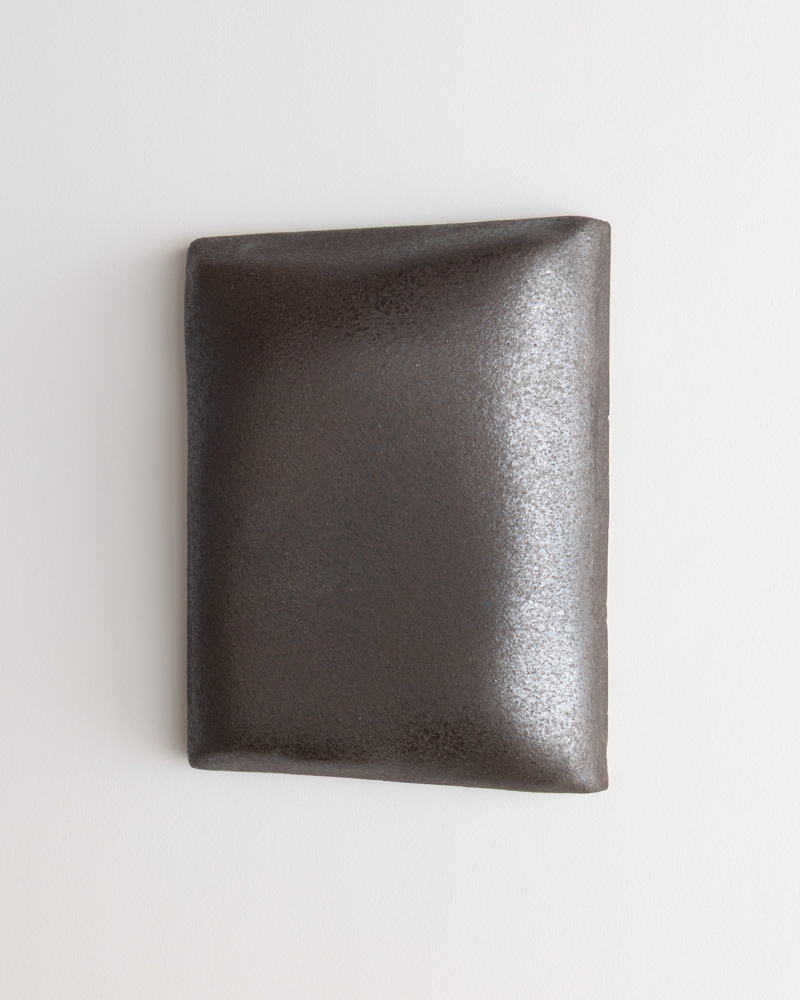 Small dark stone ceramic wall relief with softly rounded edges