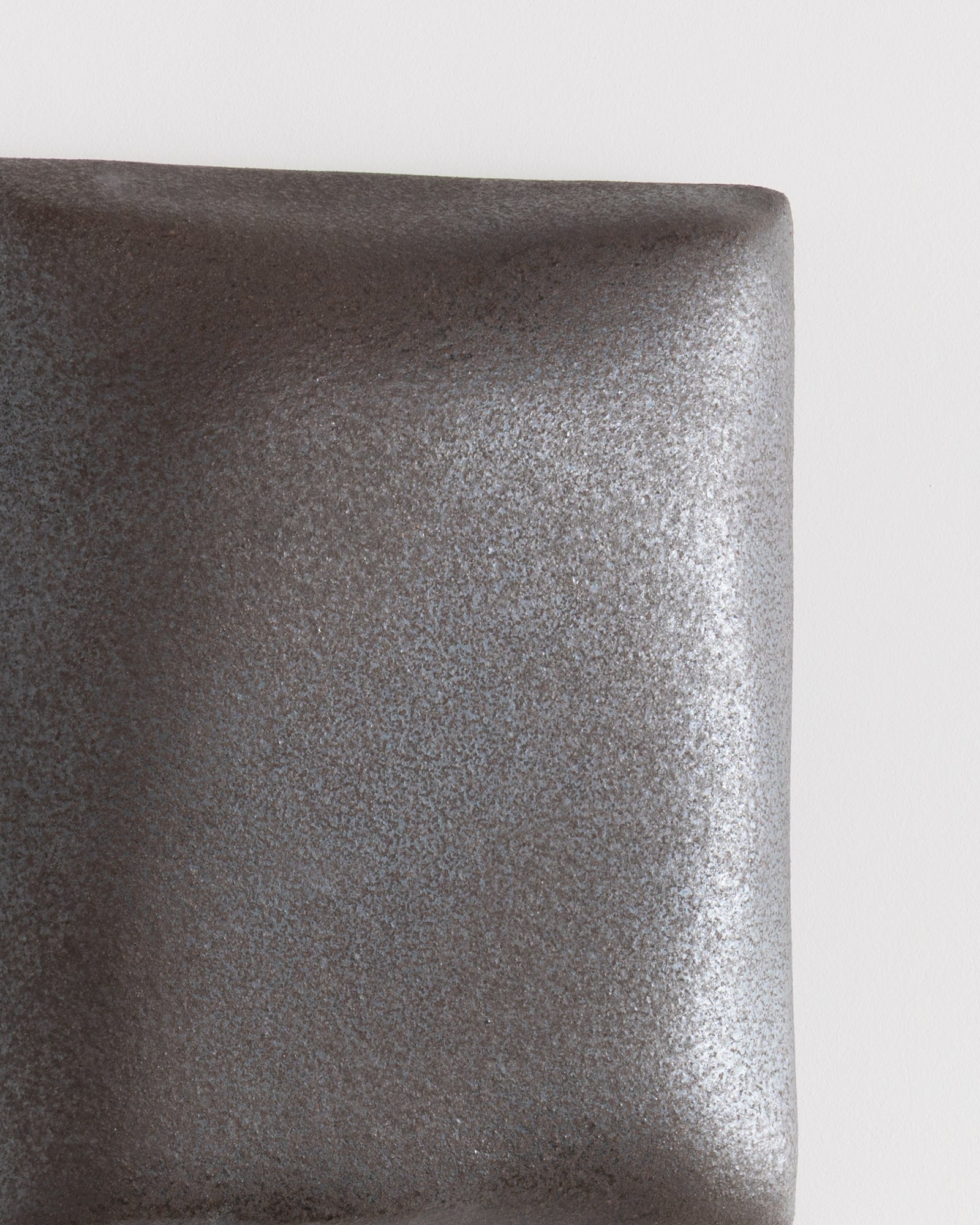 Close-up of a dark stone ceramic relief surface with fine texture