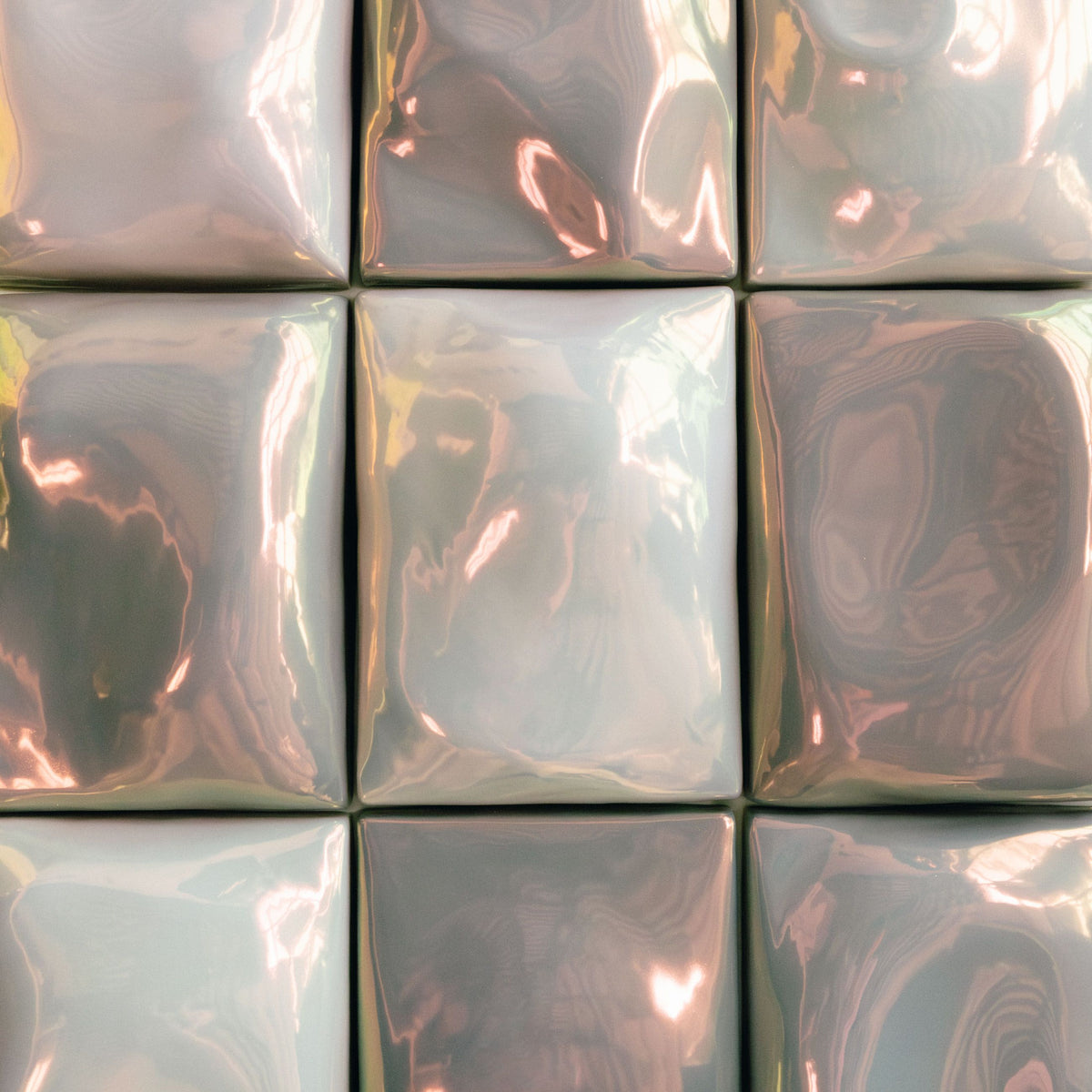 Close-up of iridescent square ceramic tiles with pink and green reflections