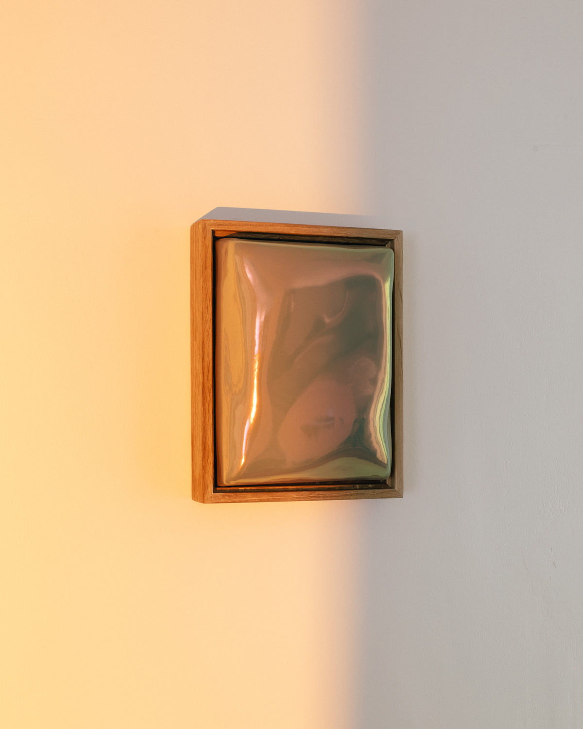 Small iridescent ceramic wall relief glowing in warm sunlight