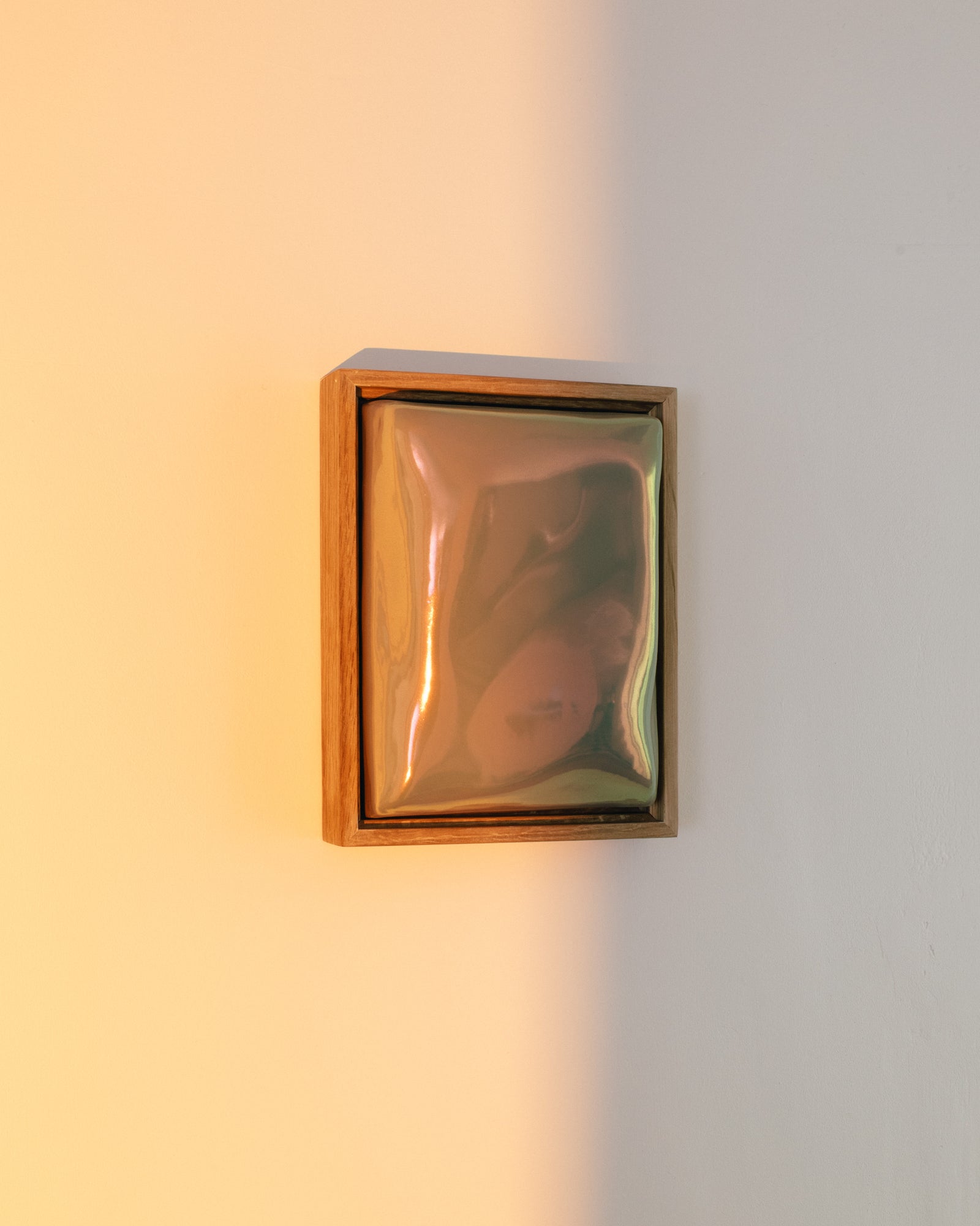 Small iridescent ceramic wall relief glowing in warm sunlight