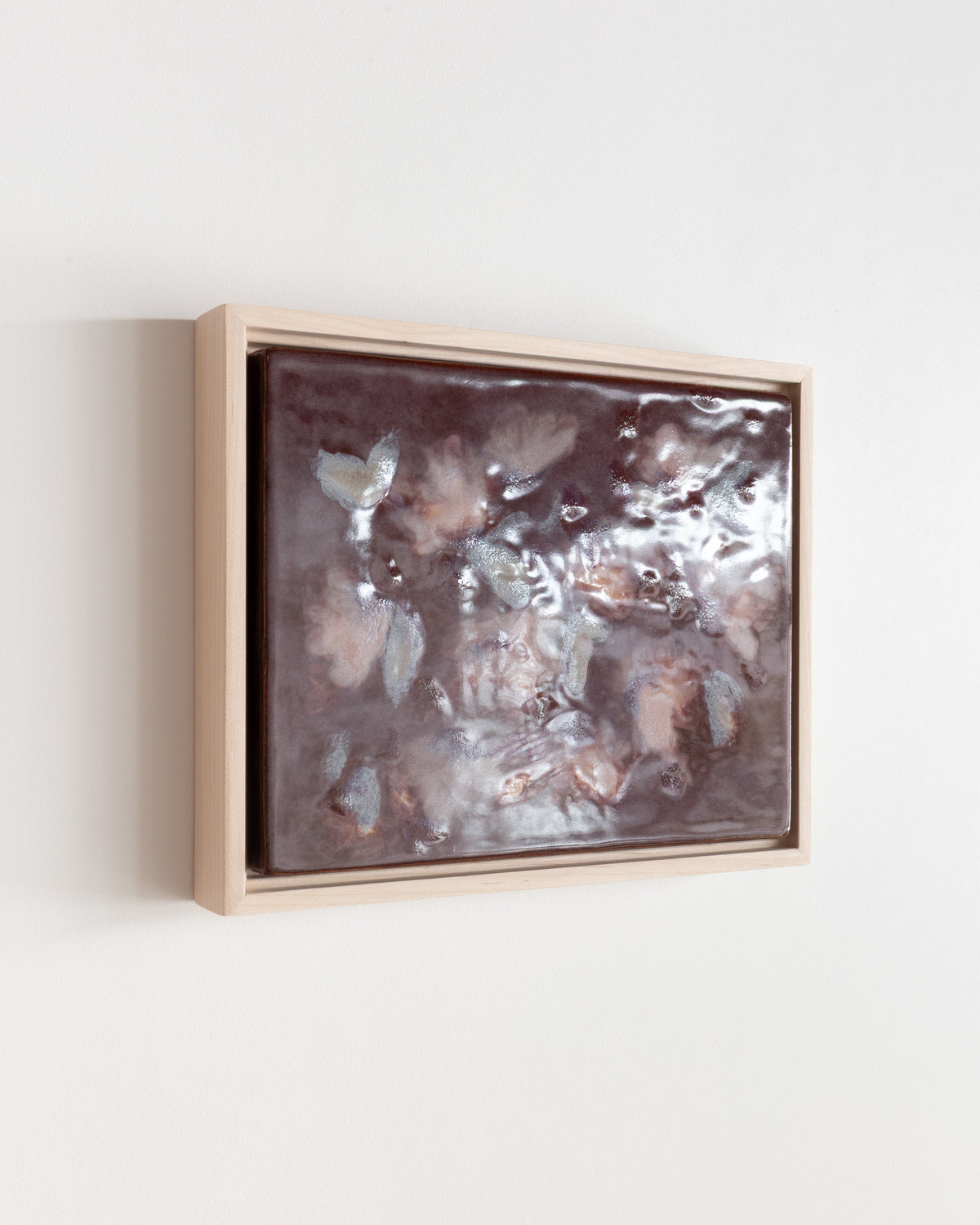 Angled detail of "Flutter" showing glossy glaze and pale petal forms in a wood frame
