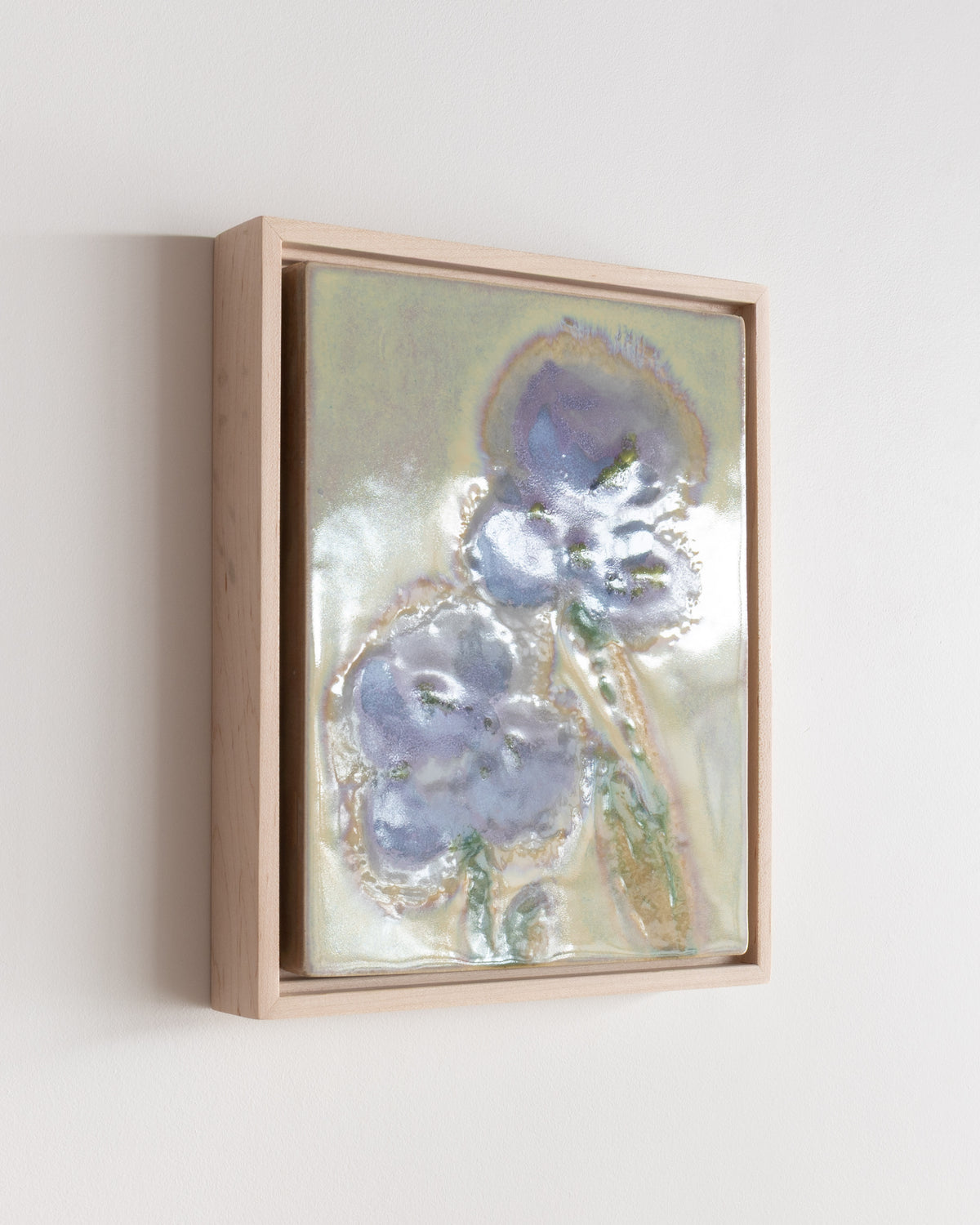 Angled detail of "A Leaning" showing blue flowers and reflective glaze in a wood frame