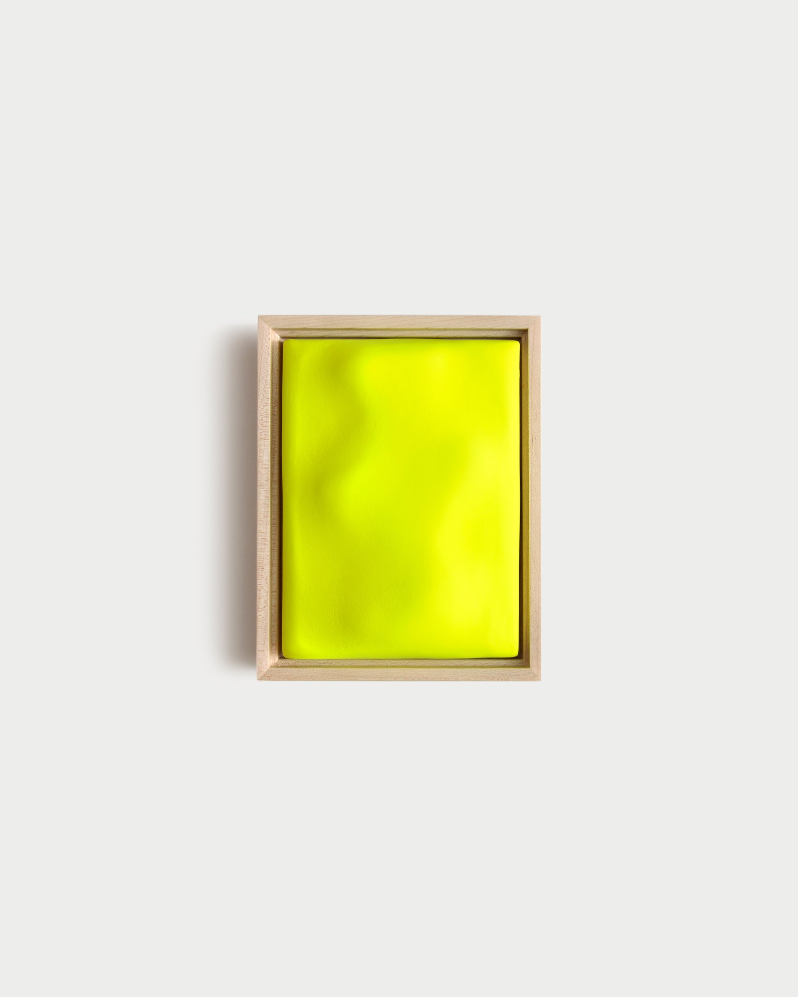 Small fluorescent yellow framed ceramic wall relief on a white wall
