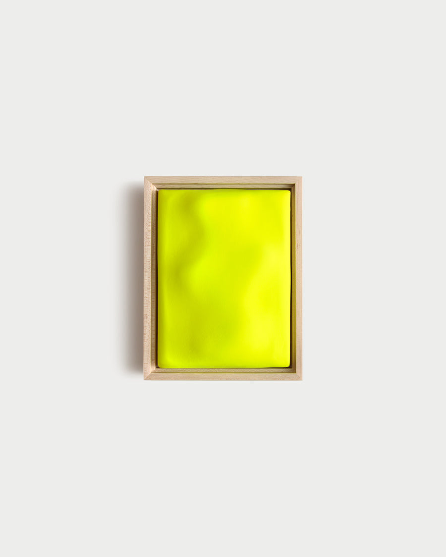 Small fluorescent yellow framed ceramic wall relief on a white wall