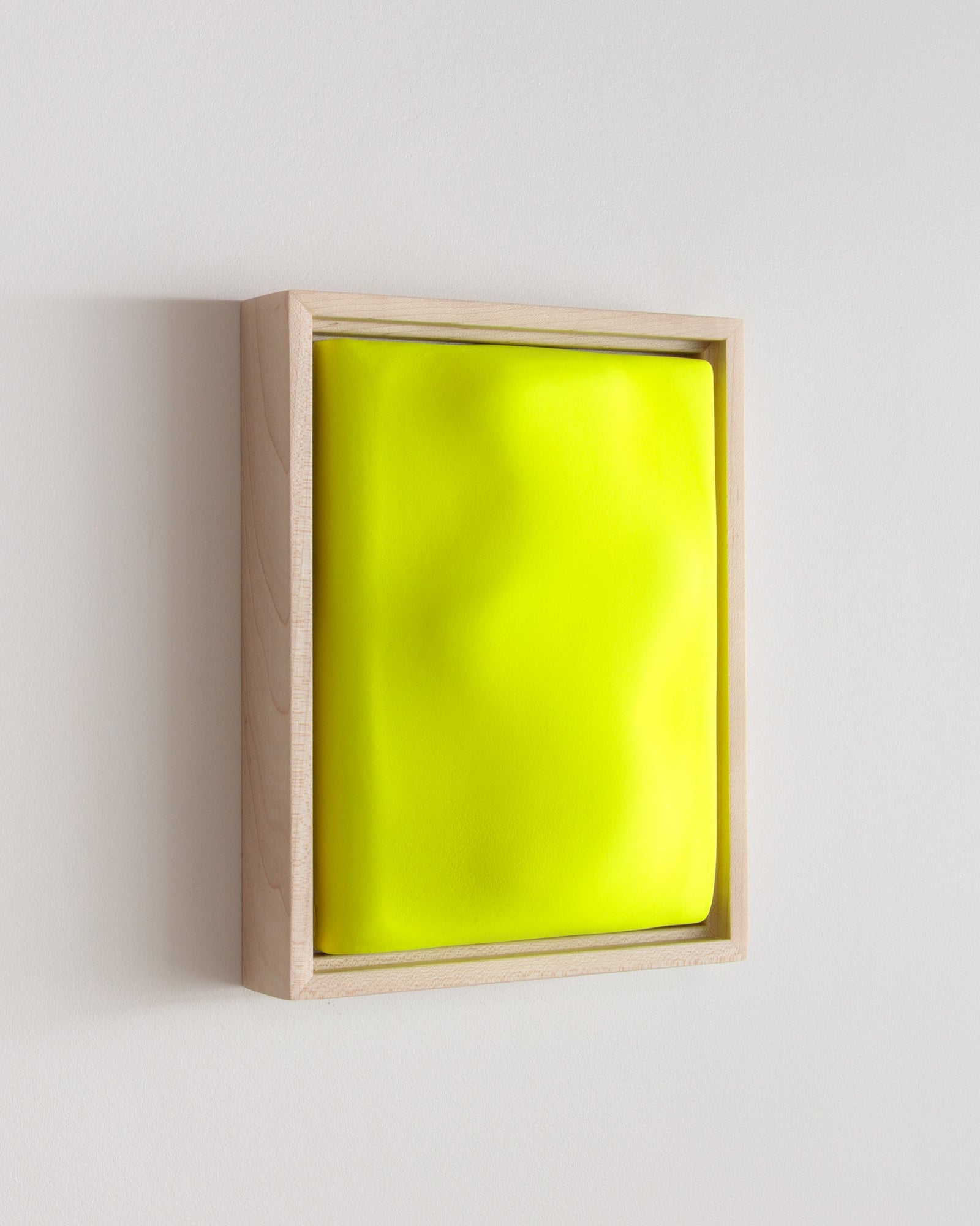 Angled side view of a fluorescent yellow framed ceramic wall relief