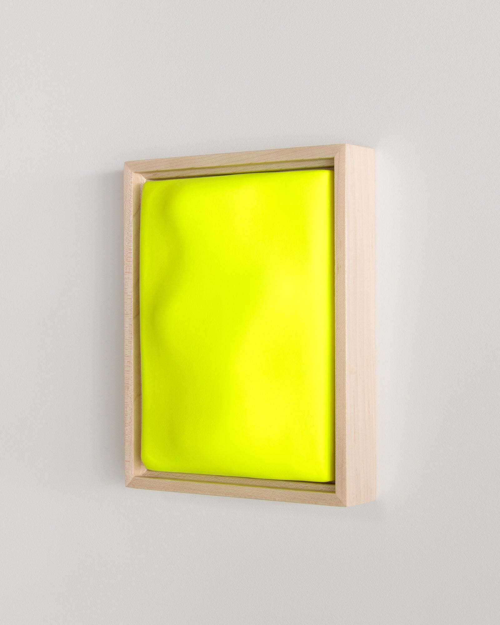 Angled view of a fluorescent yellow framed ceramic wall relief
