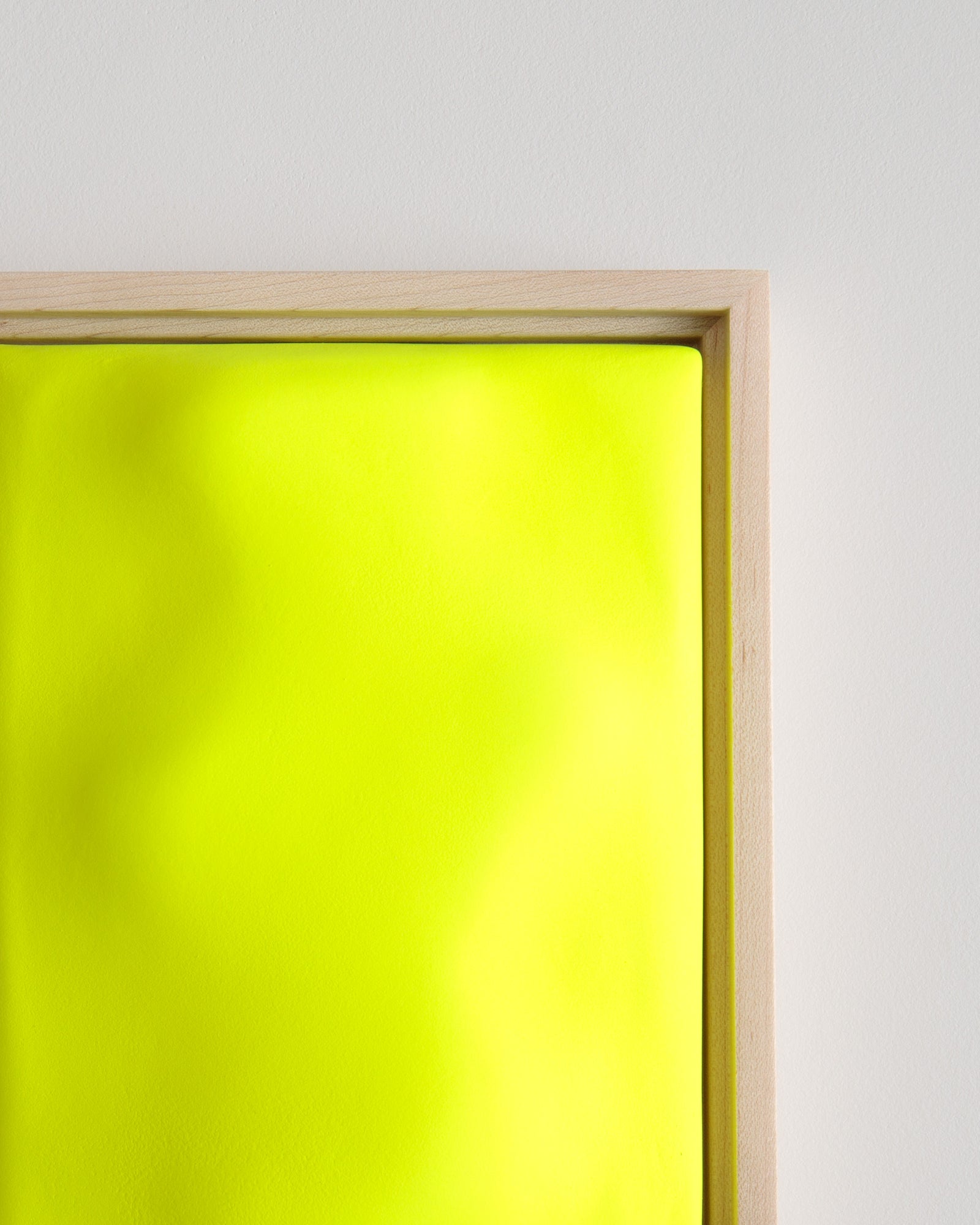 Close-up of a fluorescent yellow ceramic relief surface in a wooden frame