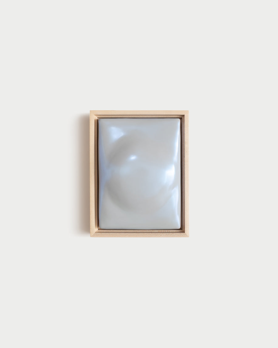 Small pale blue framed ceramic wall relief on a white wall
