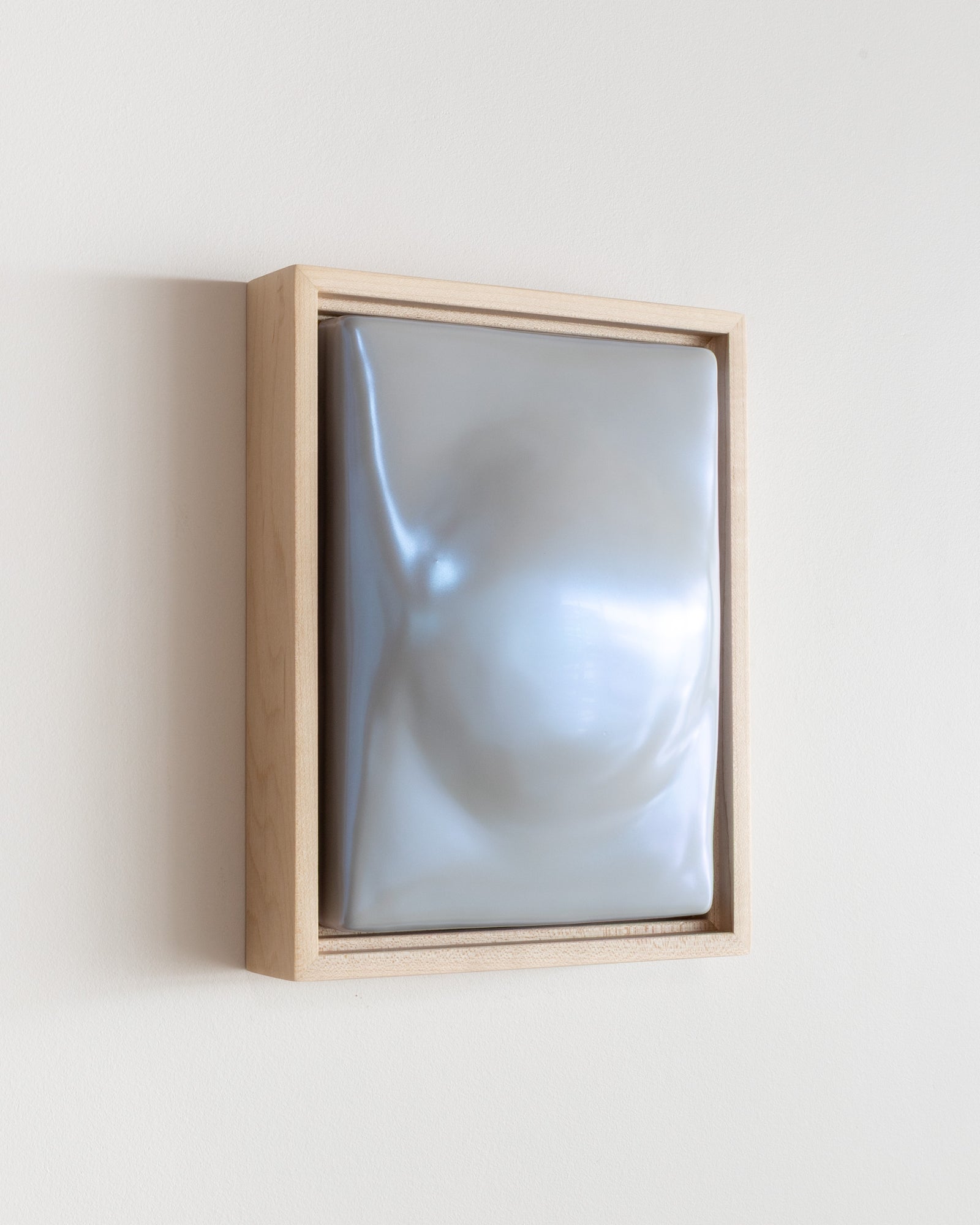 Angled view of a pale blue framed ceramic wall relief