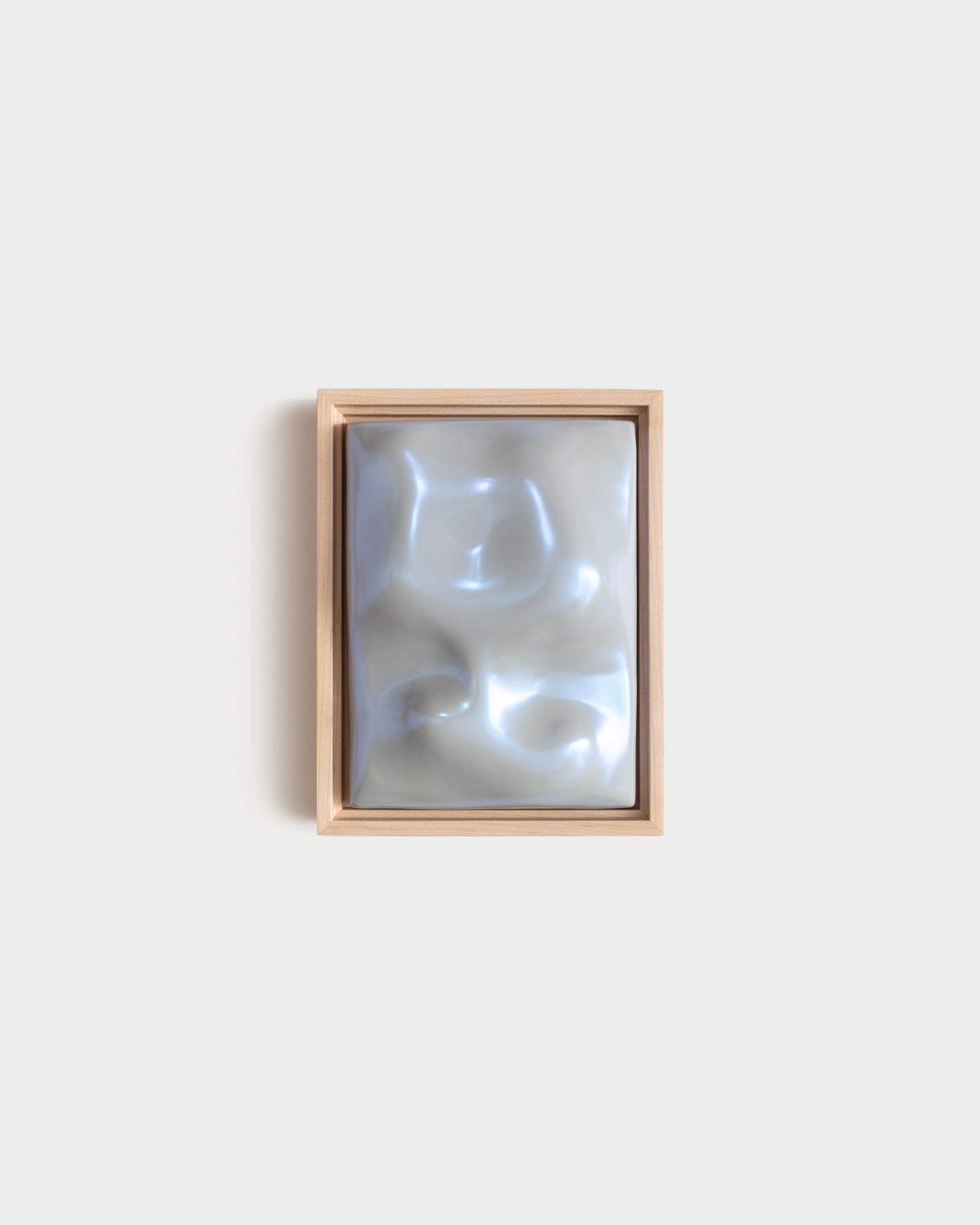 Small pale blue framed ceramic wall relief on a white wall