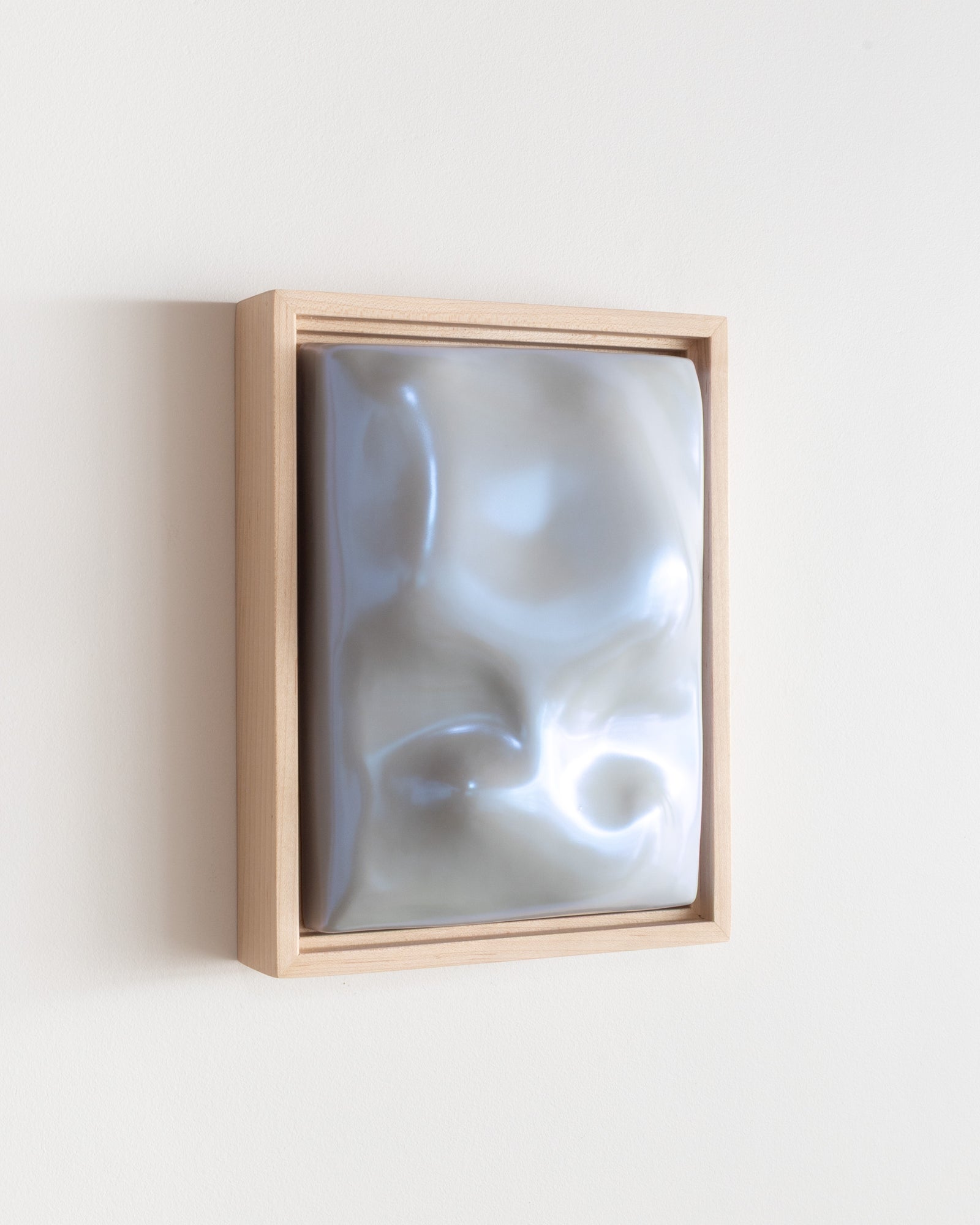 Angled side view of a pale blue framed ceramic wall relief