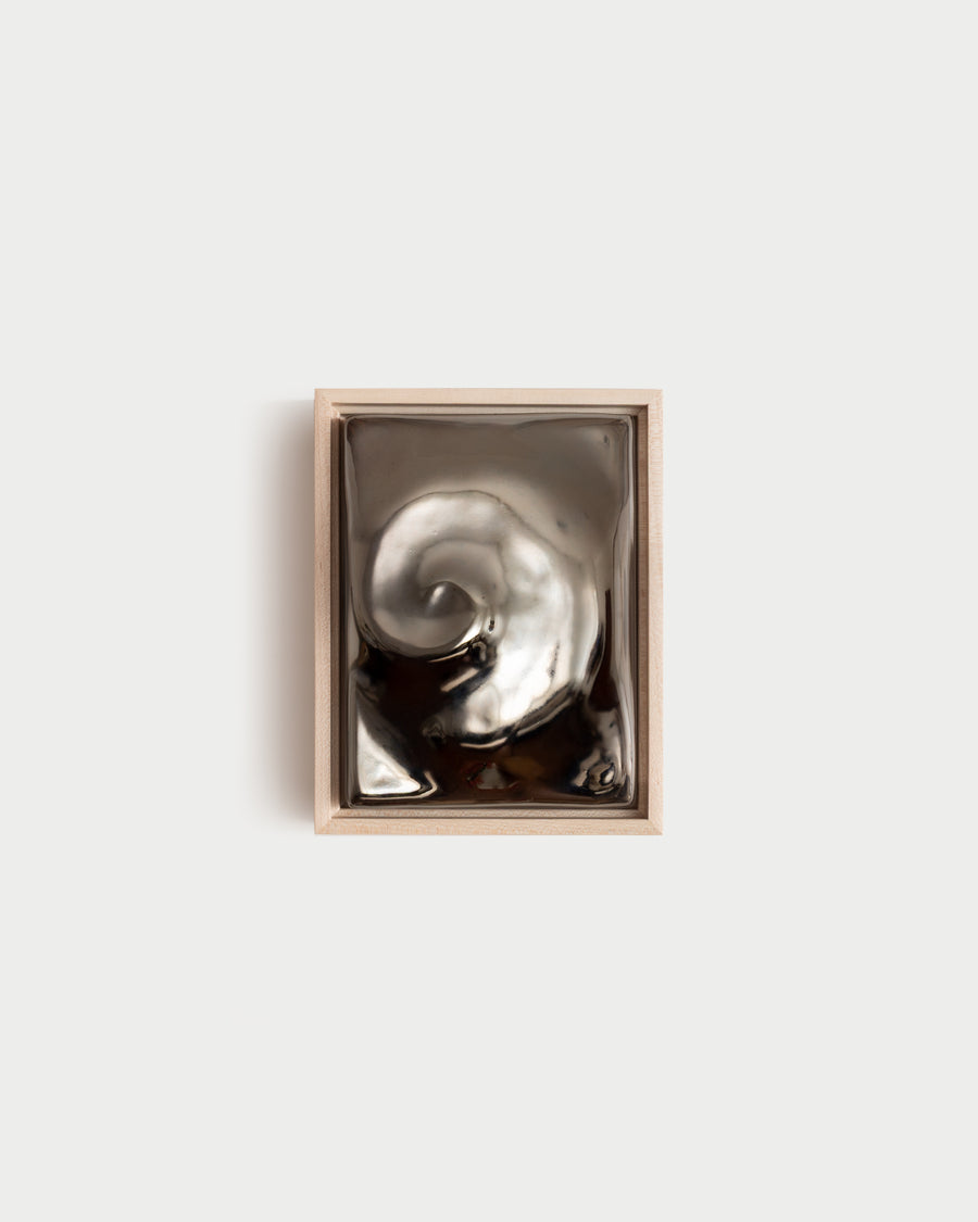 Nautilus 6x8" ceramic wall relief with a raised spiral form and dark chrome glaze