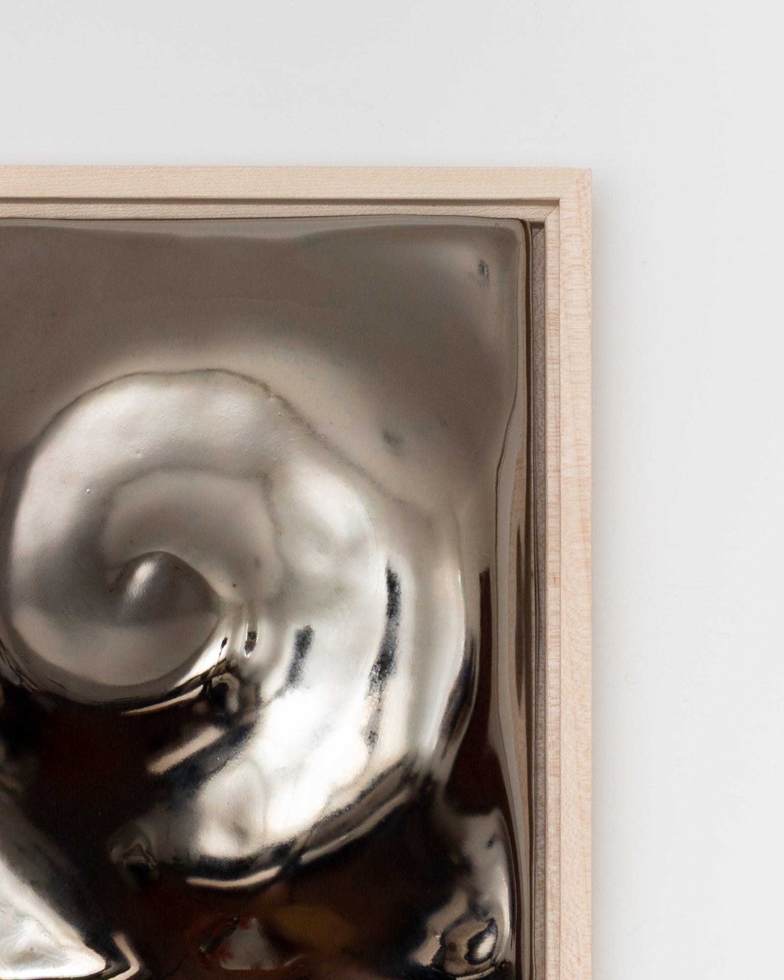 Angled detail of Nautilus showing the raised spiral form and dark chrome glaze