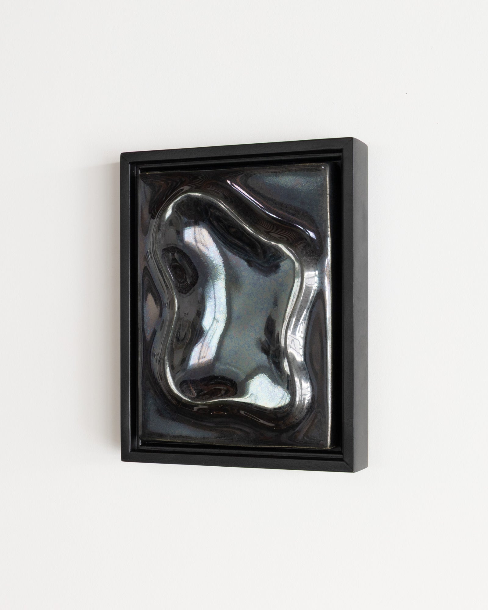 Black framed reflective ceramic wall relief with raised flowing forms