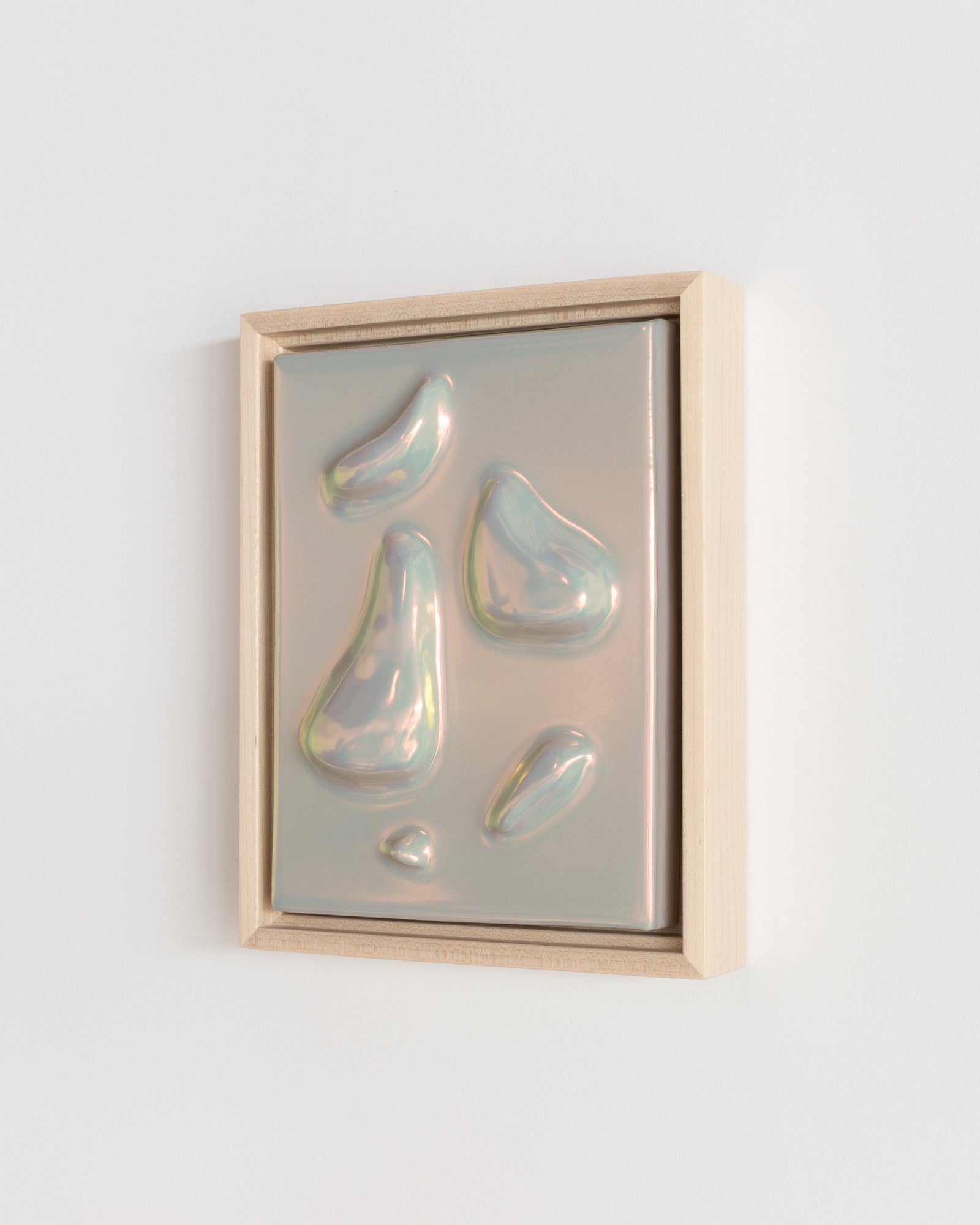 Side detail of Relics Gathering showing the framed ceramic wall relief and soft taupe iridescent glaze