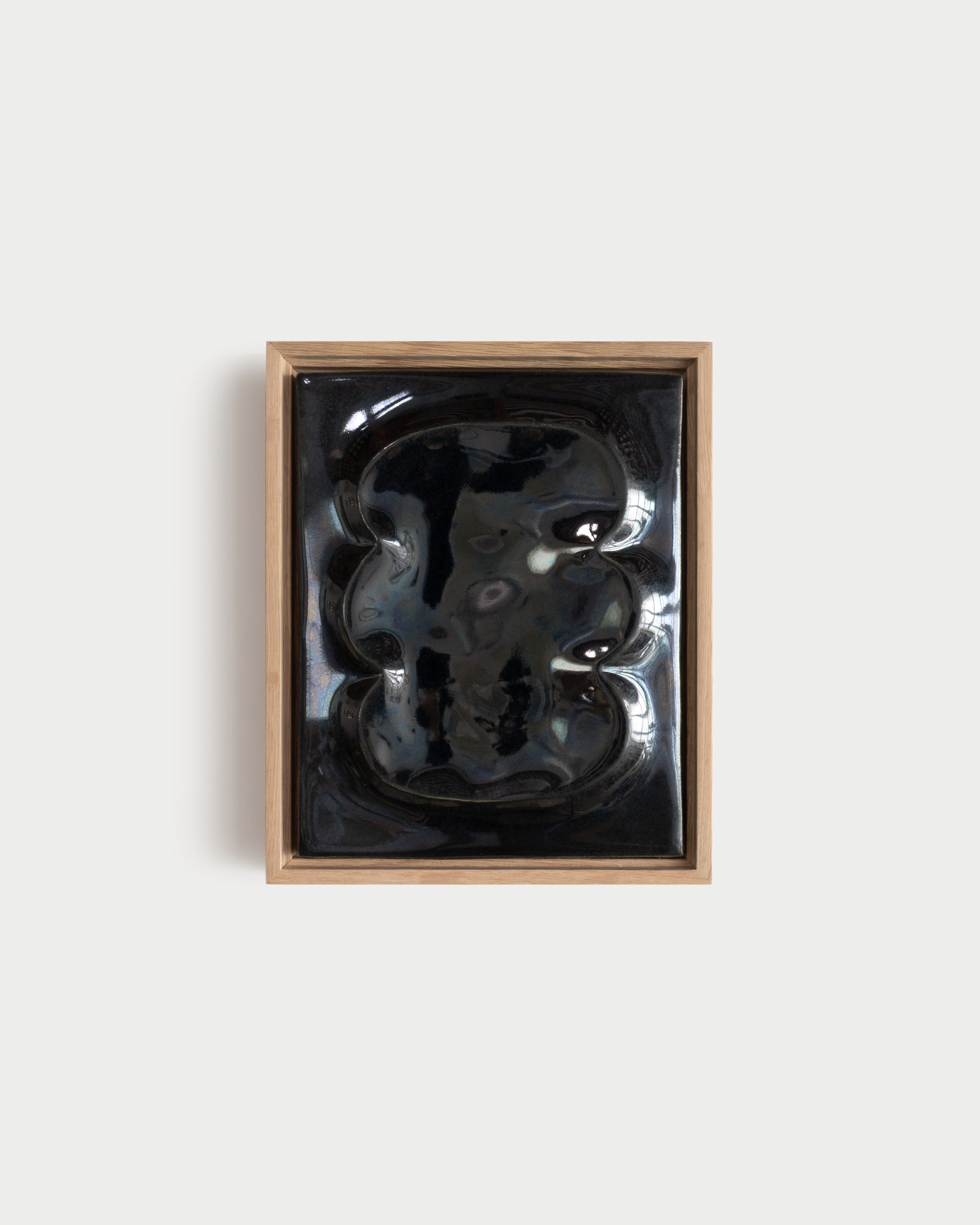 Small black framed ceramic wall relief with raised organic forms