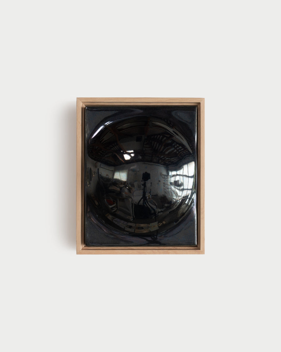 Small black framed ceramic wall relief with a large rounded form