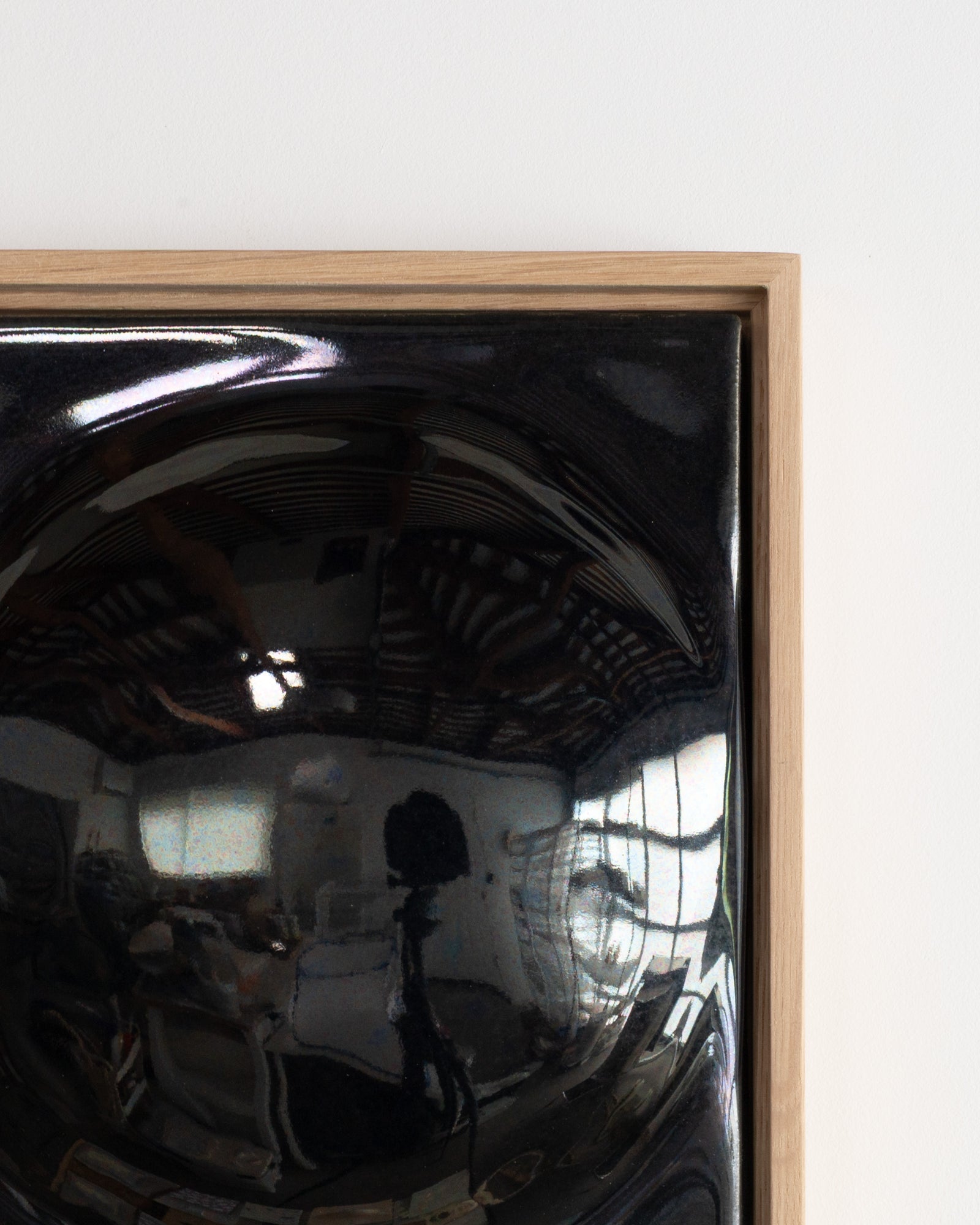 Close-up of a black glossy ceramic relief surface reflecting a room