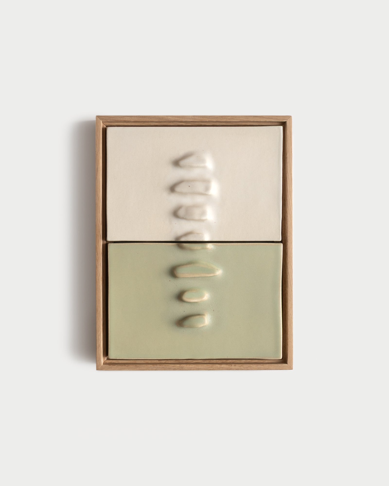 Framed two-panel ceramic wall relief in white and pale green